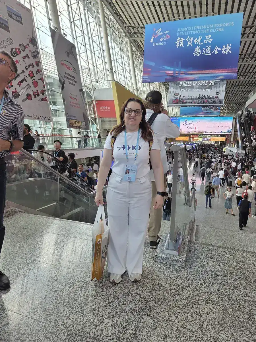 Consultora da AMO Embarque, de camiseta da agência e crachá, dentro do pavilhão da Canton Fair em Guangzhou, na China, em 2025