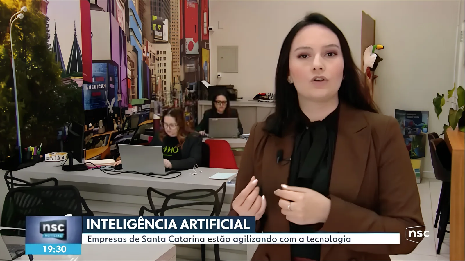 Repórter da NSC TV grava reportagem sobre inteligência artificial dentro da loja da AMO Embarque, em Chapecó, com as sócias Jamila Umar e Kadidia Umar ao fundo
